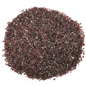 May include: A close-up of a pile of small, dark red garnet chips. The chips are irregularly shaped and have a shiny, slightly translucent appearance.