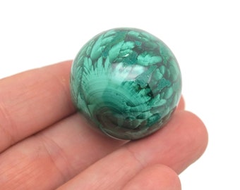 May include: A green malachite sphere with a swirling pattern. The sphere is smooth and polished.