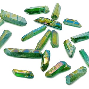May include: A collection of green iridescent quartz points, also known as aura quartz, with a variety of sizes and shapes. The points have a metallic sheen and are arranged on a white background.