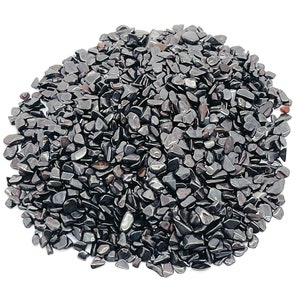 May include: A pile of polished, dark gray hematite stones. The stones are irregularly shaped and have a reflective, metallic sheen. The pile is set against a plain white background, highlighting the stones' color and texture.