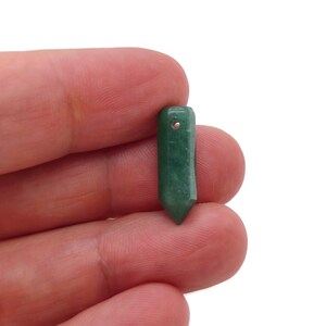 Könnte beinhalten: Ein grüner Edelstein-Anhänger in Form eines spitzen Ovals mit einem Loch oben zum Aufziehen.