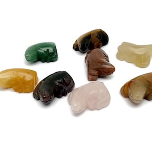 Könnte beinhalten: Eine Auswahl kleiner, geschnitzter Tierfiguren aus Stein in verschiedenen Farben, darunter Grün, Gelb, Braun und Rosa. Die Figuren sind auf weißem Grund angeordnet.