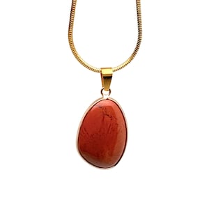 May include: A gold chain necklace with a red jasper pendant. The pendant is a smooth, oval shape with a natural, marbled pattern.