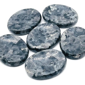 Pode incluir: Seis pedras lisas polidas de forma oval com um padrão de mármore cinza e branco. As pedras estão dispostas em semicírculo sobre um fundo branco.