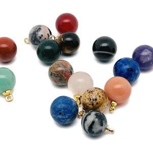 Può includere: Assortimento di 15 piccole perle rotonde di pietre preziose con anelli dorati. Le perle sono di vari colori, tra cui rosso, verde, blu, viola, marrone e rosa.