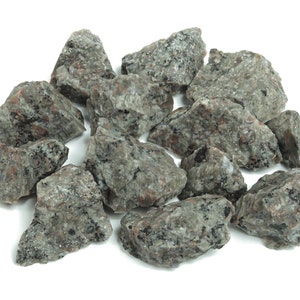 May include: A pile of small, grey and black granite rocks. The rocks are irregularly shaped and have a rough texture.
