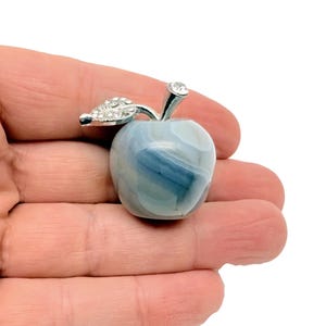 May include: A small, blue and white agate apple with a silver stem and leaf accented with rhinestones.