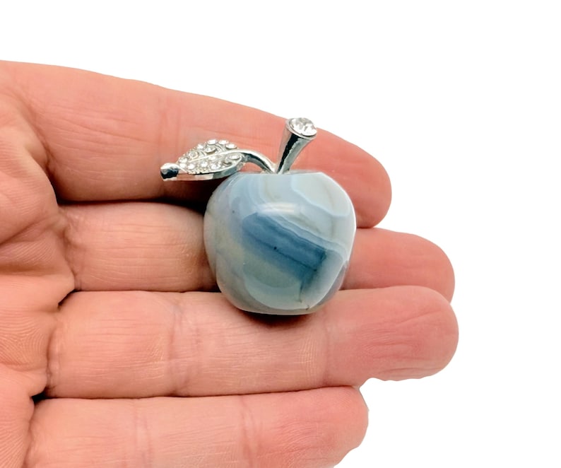 May include: A small, blue and white agate apple with a silver stem and leaf accented with rhinestones.