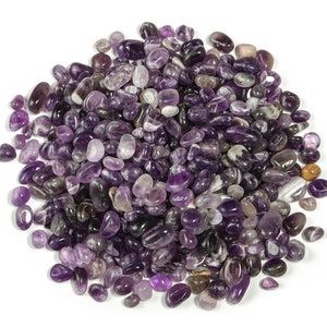 May include: A large pile of small, smooth, purple amethyst stones. The stones are tumbled and polished, and they have a variety of shapes and sizes.