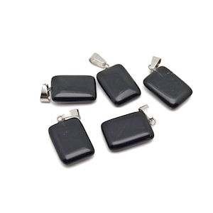 Peut inclure: Cinq pendentifs rectangulaires noirs avec des bélières argentées sont présentés sur un fond blanc. Les pendentifs sont lisses et brillants, avec un aspect poli. Les bélières sont fixées en haut de chaque pendentif, prêtes pour une chaîne ou un cordon.