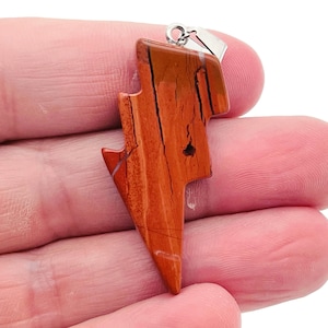 May include: Red and brown lightning bolt shaped pendant made of jasper with a silver bail.