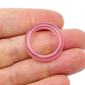 May include: A pink ring made of smooth, polished stone. The ring is thick and has a rounded shape.