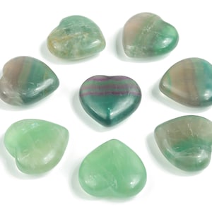 Puede incluir: Ocho piedras de fluorita en forma de corazón de color verde. Las piedras presentan diferentes tonos de verde, incluyendo verde claro, verde oscuro y algunas con toques de morado.