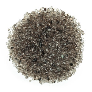 Op de afbeelding: Een hoop kleine, donkerbruine, heldere, getrommelde stenen. De stenen zijn glad en hebben een natuurlijke, aardse uitstraling.