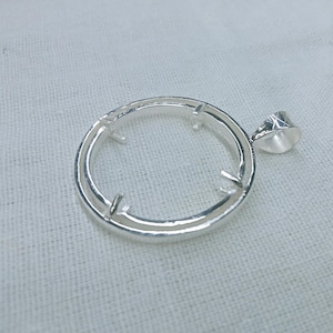 Pode incluir: Pingente de prata com uma configuração de bezel redonda e um laço de fiança. O bezel é projetado para segurar uma pedra redonda em cabochão.