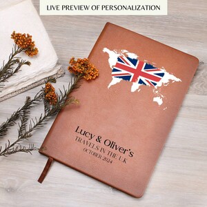 May include: A brown leather journal with a map of the world and a Union Jack flag. The journal is personalized with the text "Lucy & Oliver's Travels in the U.K. October 2024". The words "Live Preview of Personalization" are at the top.