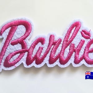 Op de afbeelding: Geborduurde patch met de naam "Barbie" in een cursief schrift, vergezeld van een paar roze lippen. De patch heeft een witte viltrug en een roze geborduurd ontwerp. Een Australische vlag staat in de rechter benedenhoek.