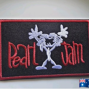 Puede incluir: Parche bordado con el nombre de la banda "Pearl Jam" en escritura roja sobre un fondo negro. El parche tiene un borde rojo y un diseño de figura de palo blanco. La bandera australiana está en la esquina inferior derecha.