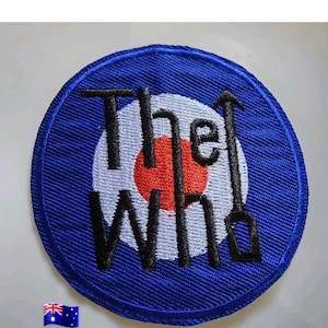 May include: A circular embroidered patch featuring a blue background with a central red and white target design. The black text reads The Who, with the letter h stylized as an arrow pointing upward. A small Australian flag icon is in the corner.