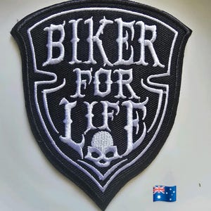 May include: Embroidered black and white patch with the text "BIKER FOR LIFE". The patch has a shield shape and a skull graphic. The Australian flag is visible in the bottom right corner. The patch is likely for a jacket or vest.