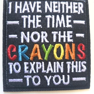 May include: A square black embroidered patch featuring white text that reads I HAVE NEITHER THE TIME NOR THE CRAYONS TO EXPLAIN THIS TO YOU. The word CRAYONS is stitched in multi-coloured thread including red, blue, orange, green, and yellow.