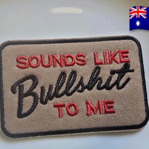 May include: A rectangular patch with the embroidered text "SOUNDS LIKE Bullshit TO ME" in red and black. The patch has a tan background and a black border. An Australian flag is in the upper right corner.