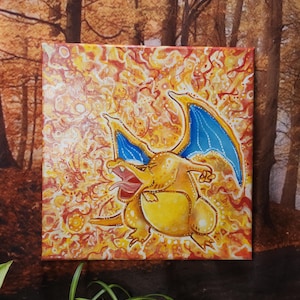 Puede incluir: Un lienzo pintado a mano con un dragón amarillo y naranja con alas azules, sobre un fondo de llamas naranja y amarillas que se arremolinan.