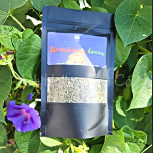May include: A black pouch with a clear window showing loose leaf tea. The label on the pouch reads "No Buzz Strawberry Green Decaf Herbal Tea"