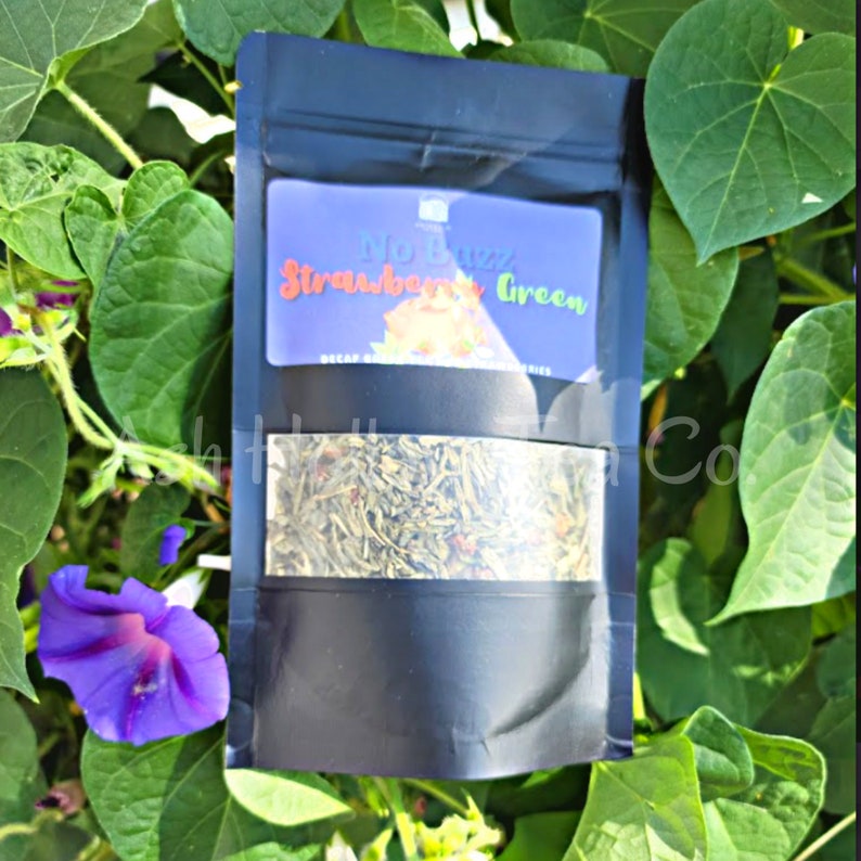May include: A black pouch with a clear window showing loose leaf tea. The label on the pouch reads "No Buzz Strawberry Green Decaf Herbal Tea"