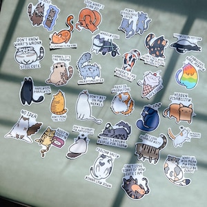 May include: A set of 24 cat-themed stickers with various humorous and relatable phrases. The stickers feature cartoon cats in different poses and expressions, with text such as "Don't know what's wrong, still cute", "Analysis paralysis", "Where's the dopamine?", "Rest is productive", "Hidden disability", "Feeling salty", "That's enough people for today", "Can't lose sight of how cute I am", and "What do you mean my pain should be zero?"