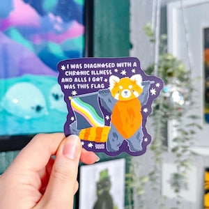 May include: A sticker featuring a cartoon red panda holding a rainbow flag. The sticker has text that reads "I WAS DIAGNOSED WITH A CHRONIC ILLNESS AND ALLS I GAT WAS THIS FLAG."