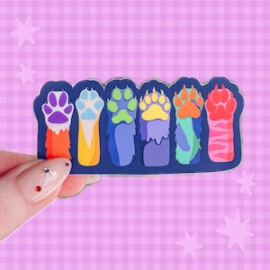 May include: A rectangular sticker featuring six distinct animal paws arranged in a row. Each paw displays a unique color palette, including purple, blue, green, yellow, orange, and pink, set against a dark blue background with a white border.