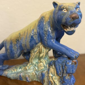 May include: A white ceramic mug with a black handle and the text "But First, Coffee" in a black, handwritten-style font. The mug is on a white surface.