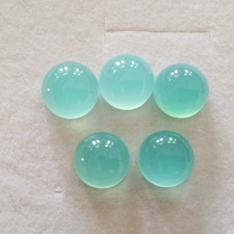 May include: Six round, smooth, light blue cabochon gemstones.
