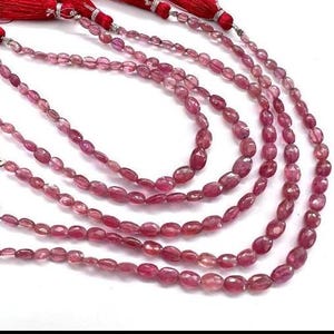 May include: A strand of pink oval-shaped gemstone beads. The beads are strung on a clear thread and are approximately 6mm in size. The beads are strung on a clear thread and are approximately 6mm in size.
