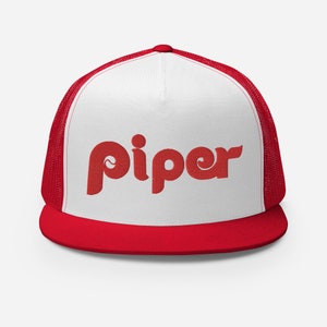 May include: A white and red trucker hat with a red embroidered logo that says "piper" on the front.
