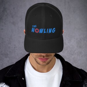 May include: Black mesh trucker hat with a blue and red embroidered logo that says "THE HOWLING"