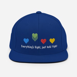 May include: A royal blue baseball cap with a white embroidered message that reads "Everything's Right, just hold tight". The message is centered on the front of the cap and is accompanied by four embroidered hearts in different colors: blue, green, red, and yellow.