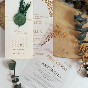 May include: Wedding invitation suite. A cream card with a green wax seal and August 2025 calendar. Additional cards with gold leaf details and text are included, tied with twine. The suite is for Francesco and Antonella.