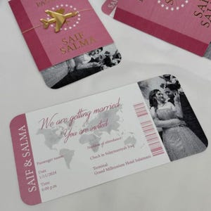 May include: Pink wedding invitation cards with gold text and a gold airplane charm. One card is designed as a passport, and another as a boarding pass, with the names "SAIF & SALMA" printed on them. The boarding pass includes the text "We are getting married. You are invited."