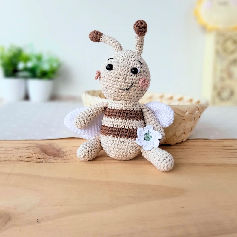 Beige edition handmade bee plush sitting on a wooden surface, natural cotton nursery toy.
