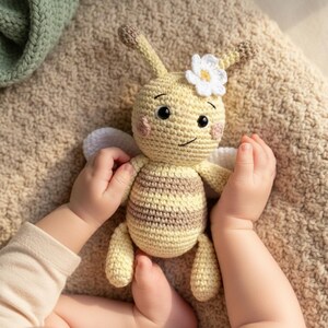 Organic bee plush held by a baby’s hands, soft crochet newborn-safe toy.
