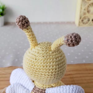 Close-up of bee plush antennas in natural cotton tones, artisan-crafted nursery keepsake.