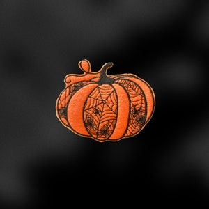 May include: Orange pumpkin with a black spiderweb design.