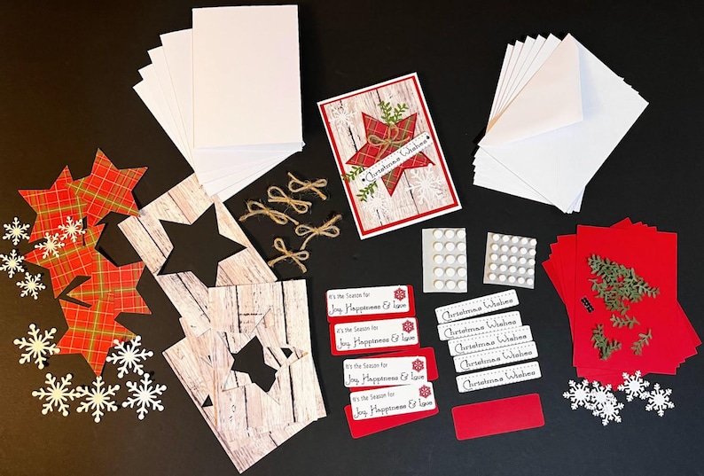 Peut inclure: Un ensemble de fournitures de bricolage sur le th&egrave;me de No&euml;l, comprenant des cartes vierges, des enveloppes, des d&eacute;coupes en forme d'&eacute;toile et des &eacute;l&eacute;ments d&eacute;coratifs. La palette de couleurs comprend des tons rouges, blancs et bruns, avec des accents de vert et d'or. Le texte "Christmas Wishes".