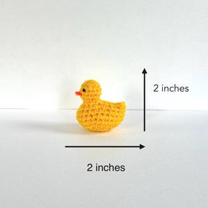 May include: A small yellow crocheted rubber duck measuring 2 inches in length and 2 inches in height.