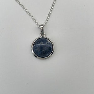 May include: A silver chain necklace with a round pendant featuring a blue and white gemstone.