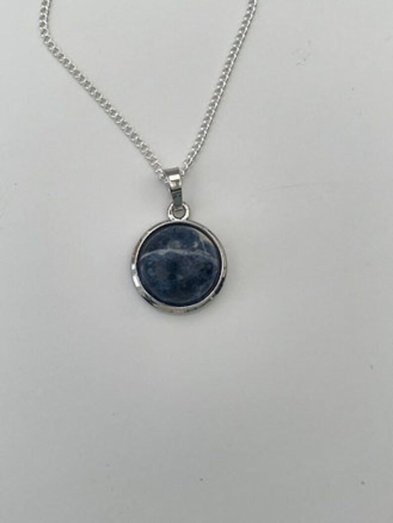 May include: A silver chain necklace with a round pendant featuring a blue and white gemstone.