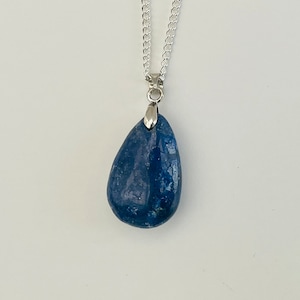 K&ouml;nnte beinhalten: Halskette mit einem tropfenf&ouml;rmigen, blauen Anh&auml;nger. Der Anh&auml;nger ist ein tiefblauer Stein mit einer silberfarbenen Metallkappe und Kette. Die Kette ist ein filigranes, verbundenes Design.