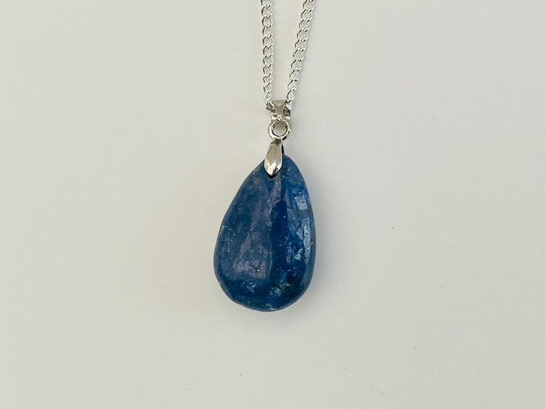 K&ouml;nnte beinhalten: Halskette mit einem tropfenf&ouml;rmigen, blauen Anh&auml;nger. Der Anh&auml;nger ist ein tiefblauer Stein mit einer silberfarbenen Metallkappe und Kette. Die Kette ist ein filigranes, verbundenes Design.